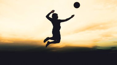 Bir voleybol oyuncusunun silueti dağda pratik yapıyor ve akşam çok güzel bir manzara sunuyor.