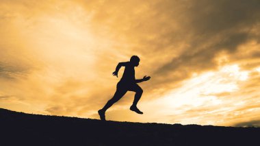 Akşamları güzel manzaralı dağlarda antrenman yapan koşucuların silueti.