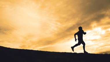 Akşamları güzel manzaralı dağlarda antrenman yapan koşucuların silueti.