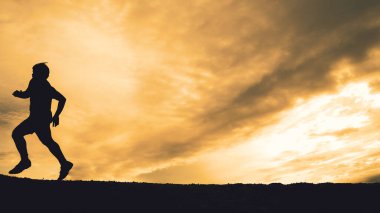 Akşamları güzel manzaralı dağlarda antrenman yapan koşucuların silueti.