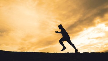 Akşamları güzel manzaralı dağlarda antrenman yapan koşucuların silueti.