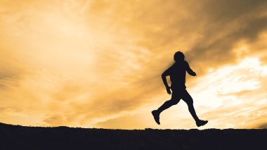 Akşamları güzel manzaralı dağlarda antrenman yapan koşucuların silueti.