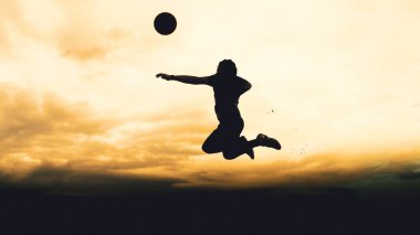 Bir voleybol oyuncusunun silueti dağda pratik yapıyor ve akşam çok güzel bir manzara sunuyor.