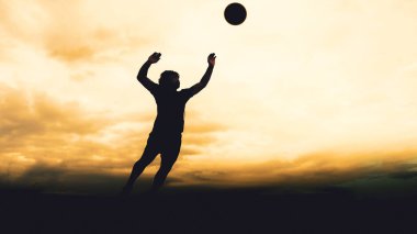Bir voleybol oyuncusunun silueti dağda pratik yapıyor ve akşam çok güzel bir manzara sunuyor.