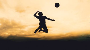 Bir voleybol oyuncusunun silueti dağda pratik yapıyor ve akşam çok güzel bir manzara sunuyor.