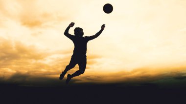 Bir voleybol oyuncusunun silueti dağda pratik yapıyor ve akşam çok güzel bir manzara sunuyor.