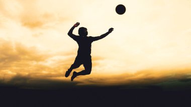 Bir voleybol oyuncusunun silueti dağda pratik yapıyor ve akşam çok güzel bir manzara sunuyor.