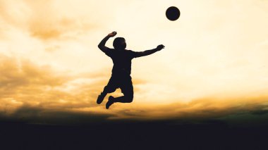 Bir voleybol oyuncusunun silueti dağda pratik yapıyor ve akşam çok güzel bir manzara sunuyor.