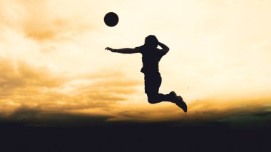 Bir voleybol oyuncusunun silueti dağda pratik yapıyor ve akşam çok güzel bir manzara sunuyor.