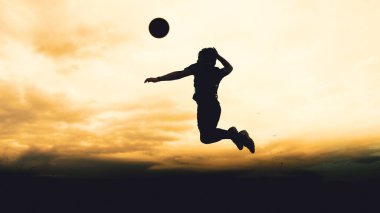 Bir voleybol oyuncusunun silueti dağda pratik yapıyor ve akşam çok güzel bir manzara sunuyor.