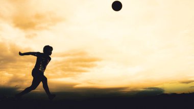 Bir voleybol oyuncusunun silueti dağda pratik yapıyor ve akşam çok güzel bir manzara sunuyor.