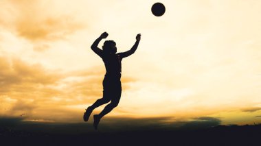 Bir voleybol oyuncusunun silueti dağda pratik yapıyor ve akşam çok güzel bir manzara sunuyor.