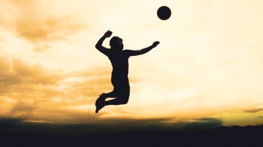Bir voleybol oyuncusunun silueti dağda pratik yapıyor ve akşam çok güzel bir manzara sunuyor.