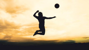 Bir voleybol oyuncusunun silueti dağda pratik yapıyor ve akşam çok güzel bir manzara sunuyor.