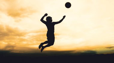 Bir voleybol oyuncusunun silueti dağda pratik yapıyor ve akşam çok güzel bir manzara sunuyor.