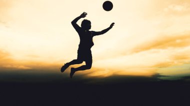 Bir voleybol oyuncusunun silueti dağda pratik yapıyor ve akşam çok güzel bir manzara sunuyor.