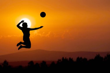 Bir plaj voleybolcusunun silueti atlayıp voleybol topuna vuruyor..
