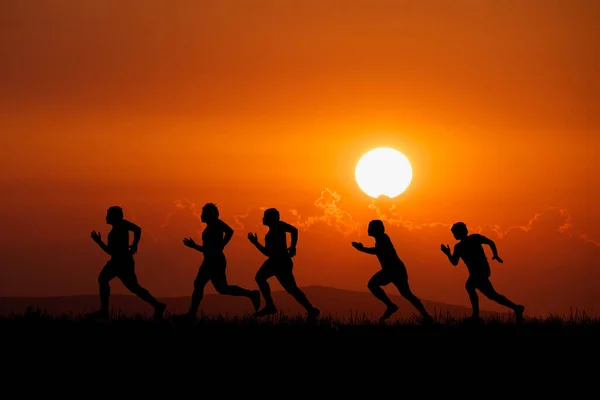 Silhouette of runners training in the mountains with beautiful views in the evening.A group of runners practicing outdoor running in the evening. sports training concep