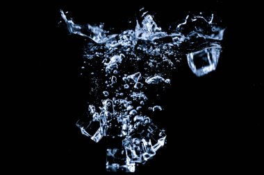 Su, siyah arkaplanda izole edilmiş buz küpleriyle soyut bir şekil alır..