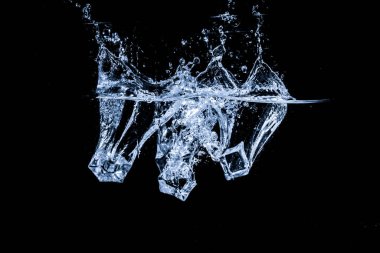 Su, siyah arkaplanda izole edilmiş buz küpleriyle soyut bir şekil alır..