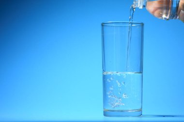 Mavi arka planda bardakta temiz içme suyu. sağlıklı içme suyu kavramı
