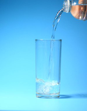 Mavi arka planda bardakta temiz içme suyu. sağlıklı içme suyu kavramı