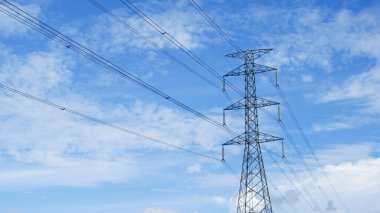 Tayland kırsalında yüksek voltajlı elektrik direkleri. Güzel bulutlu bir gökyüzünün arka planında tarladan geçen yüksek voltajlı elektrik hatları..