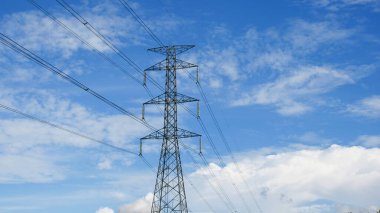 Tayland kırsalında yüksek voltajlı elektrik direkleri. Güzel bulutlu bir gökyüzünün arka planında tarladan geçen yüksek voltajlı elektrik hatları..