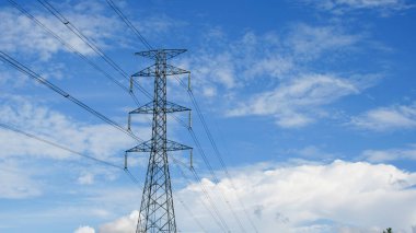 Tayland kırsalında yüksek voltajlı elektrik direkleri. Güzel bulutlu bir gökyüzünün arka planında tarladan geçen yüksek voltajlı elektrik hatları..