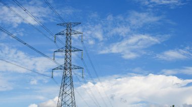 Tayland kırsalında yüksek voltajlı elektrik direkleri. Güzel bulutlu bir gökyüzünün arka planında tarladan geçen yüksek voltajlı elektrik hatları..