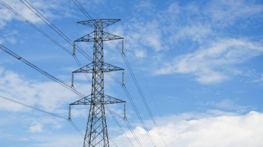 Tayland kırsalında yüksek voltajlı elektrik direkleri. Güzel bulutlu bir gökyüzünün arka planında tarladan geçen yüksek voltajlı elektrik hatları..