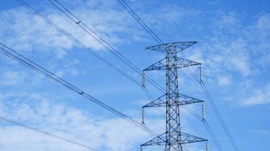 Tayland kırsalında yüksek voltajlı elektrik direkleri. Güzel bulutlu bir gökyüzünün arka planında tarladan geçen yüksek voltajlı elektrik hatları..