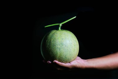 Siyah bir arka planda ikiye bölünmüş bir el kavun