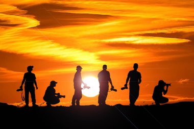 Profesyonel bir peyzaj fotoğrafçısının silueti dağda bir kamera tutuyor. Akşamları birçok profesyonel fotoğrafçının siluetleri.