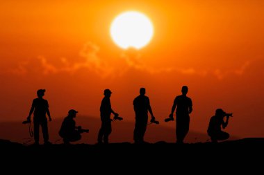 Profesyonel bir peyzaj fotoğrafçısının silueti dağda bir kamera tutuyor. Akşamları birçok profesyonel fotoğrafçının siluetleri.