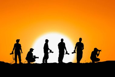 Profesyonel bir peyzaj fotoğrafçısının silueti dağda bir kamera tutuyor. Akşamları birçok profesyonel fotoğrafçının siluetleri.