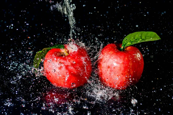 黒い背景に水の中の赤いリンゴが飛び散った 黒の背景にアップルウォータースプラッシュ — ストック写真