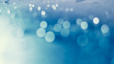 Mavi bokeh parçacıkları, toz gradyan soyut arkaplanı ödüllendirir. Mavi arkaplanda uzayda fütürist ışıltı. 