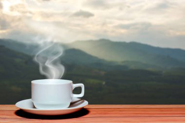 Bir fincan sıcak beyaz kahve ve güzel bir manzarası var..