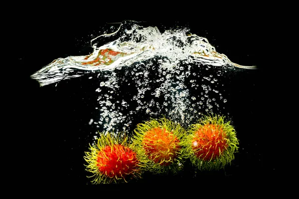 Rambutan, Thai fruit in splashing water on a black background. refreshing