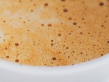 Beyaz bir fincanda köpüklü kahve yakın plan.