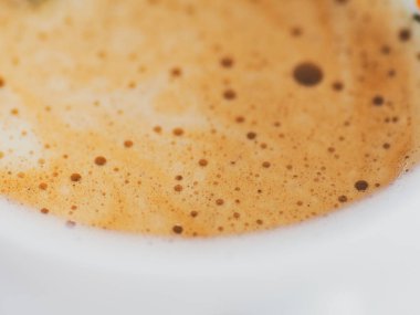 Beyaz bir fincanda köpüklü kahve yakın plan.