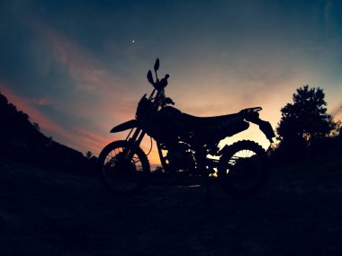 Gün batımında arka planda motosiklet silueti