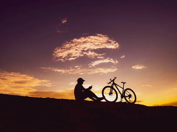 silhouette of man with a mountain bike on sunset background