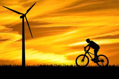 Bir adam temiz enerji üreten rüzgar türbinleri arasında bisiklet sürüyor. temiz enerji kavramı
