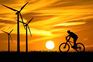 Bir adam temiz enerji üreten rüzgar türbinleri arasında bisiklet sürüyor. temiz enerji kavramı