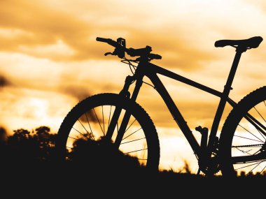 Akşamleyin çayıra park etmiş bir dağ bisikleti. bisiklet silueti