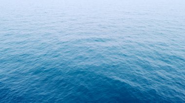 Denizin engin ve sakin havasını gösteren, yumuşak dalgalarla okyanus yüzeyinin huzurlu bir görüntüsü..