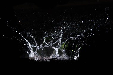 Su damlacıklarının hızlı bir şekilde gölgeye çarpması, dinamik hareket ve akıcılığı gösteriyor..