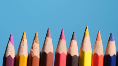 Canlı bir mavi arka plana karşı renkli kalemler dizisi, sanat, yaratıcılık ve tasarım temaları için mükemmel..